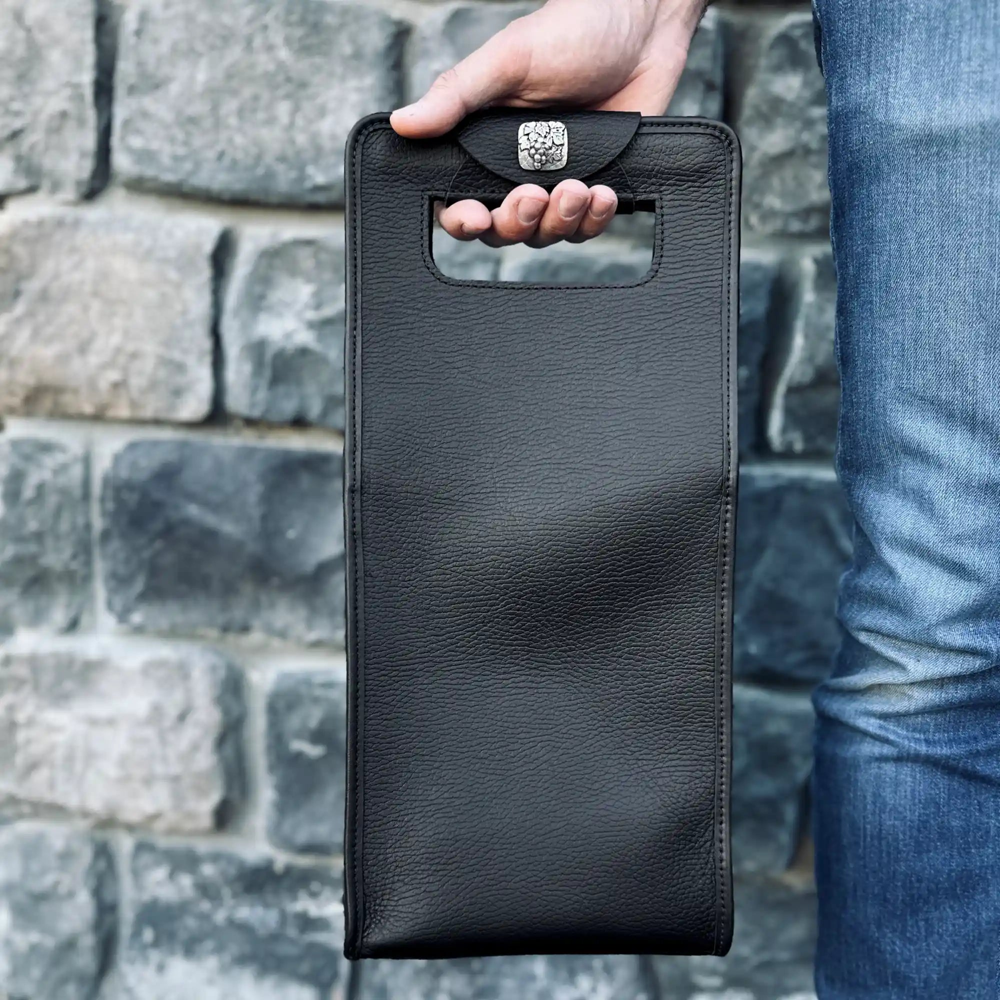 Leather Wine Carrier Bag, double, black pebbled leather, against a rock wall, Sonoma County Leather